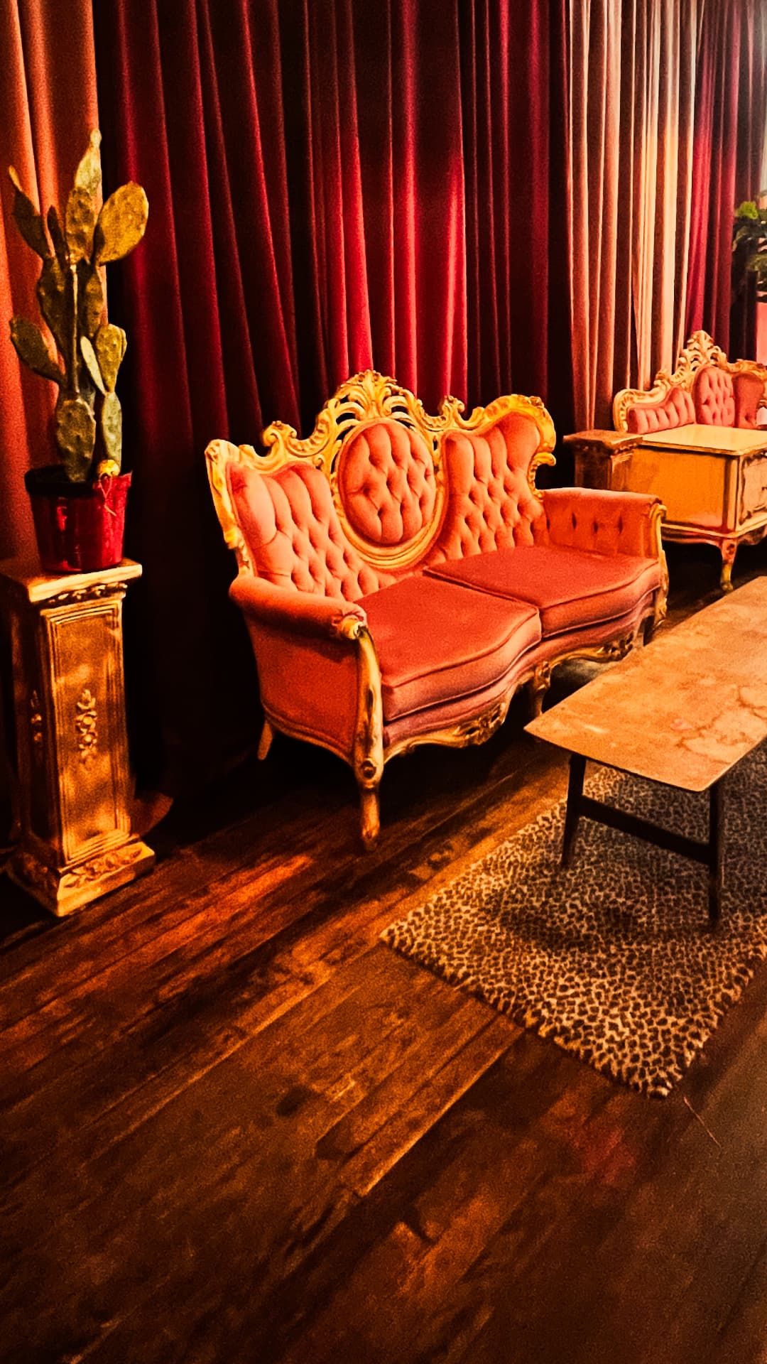 Pink vintage sofa against red velvet curtains