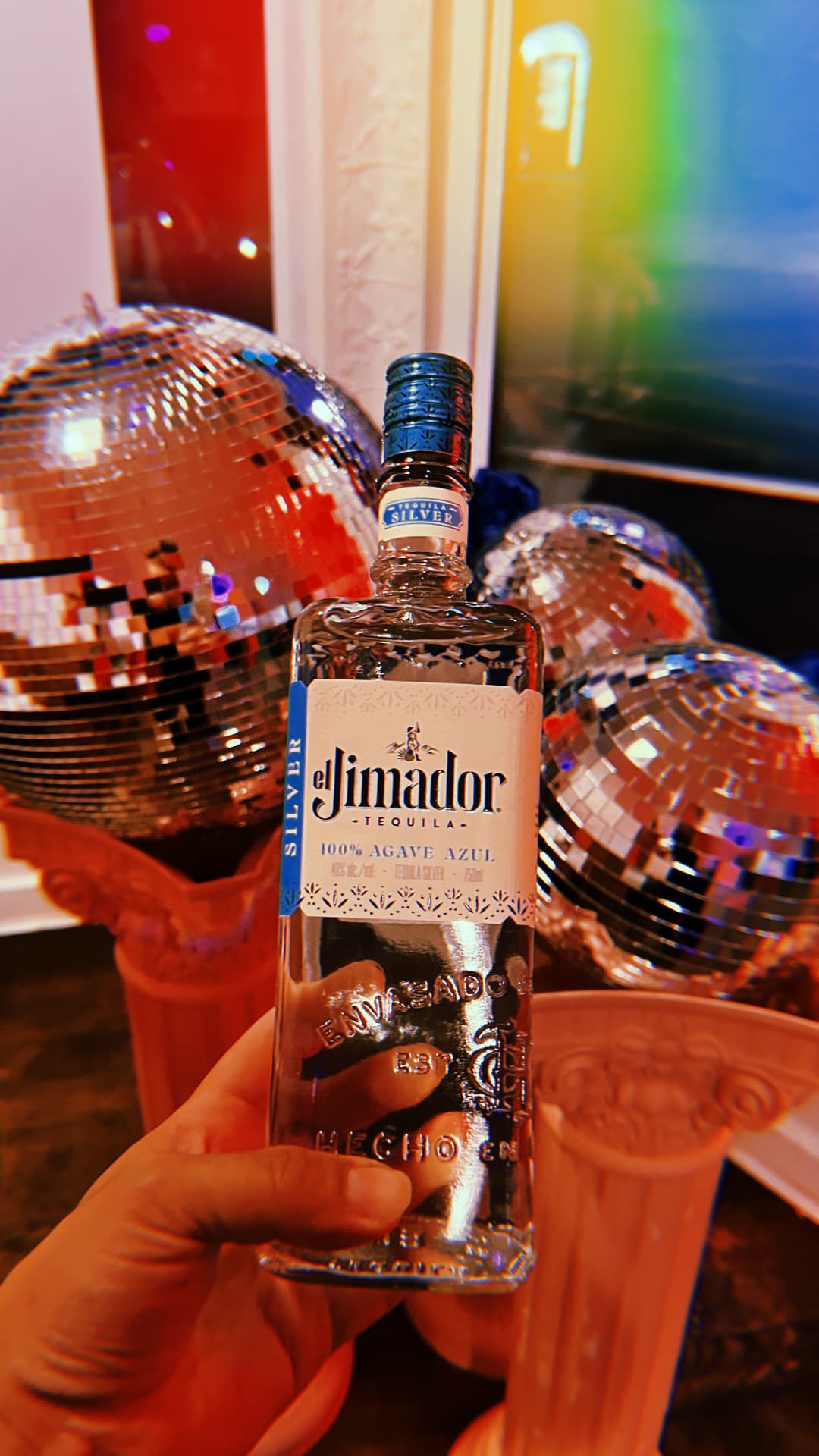 Bottle of tequila held in front of disco balls