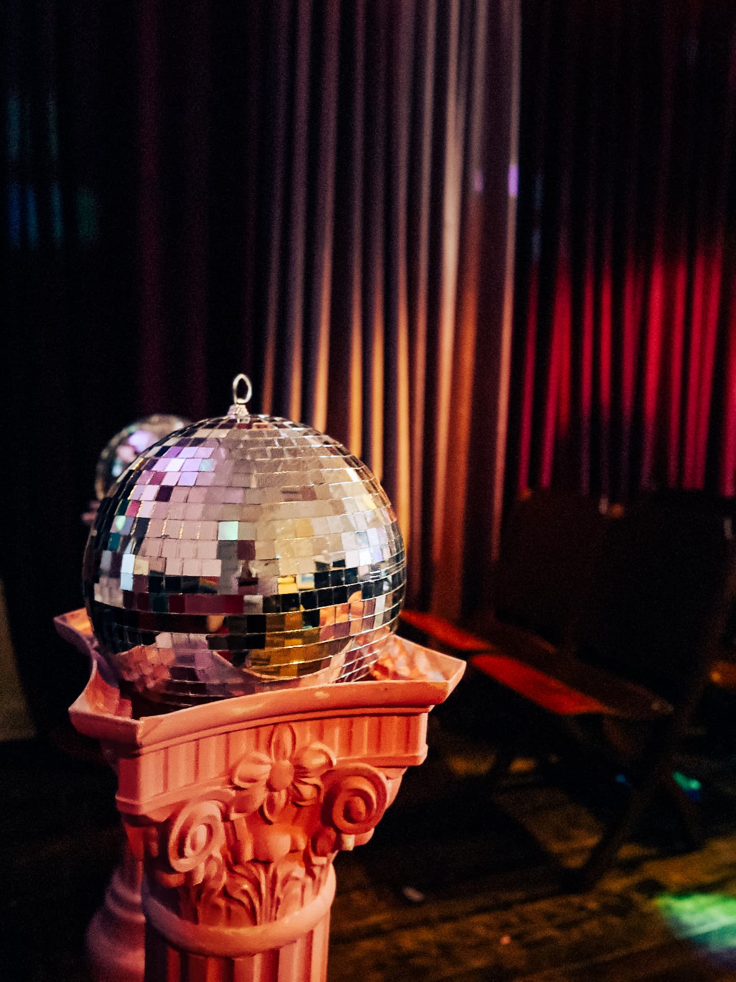 Disco ball resting on a pink ornate column